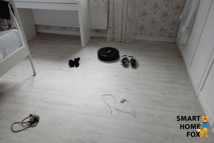 Roborock S6 MaxV стоит на полу перед подготовленными препятствиями.